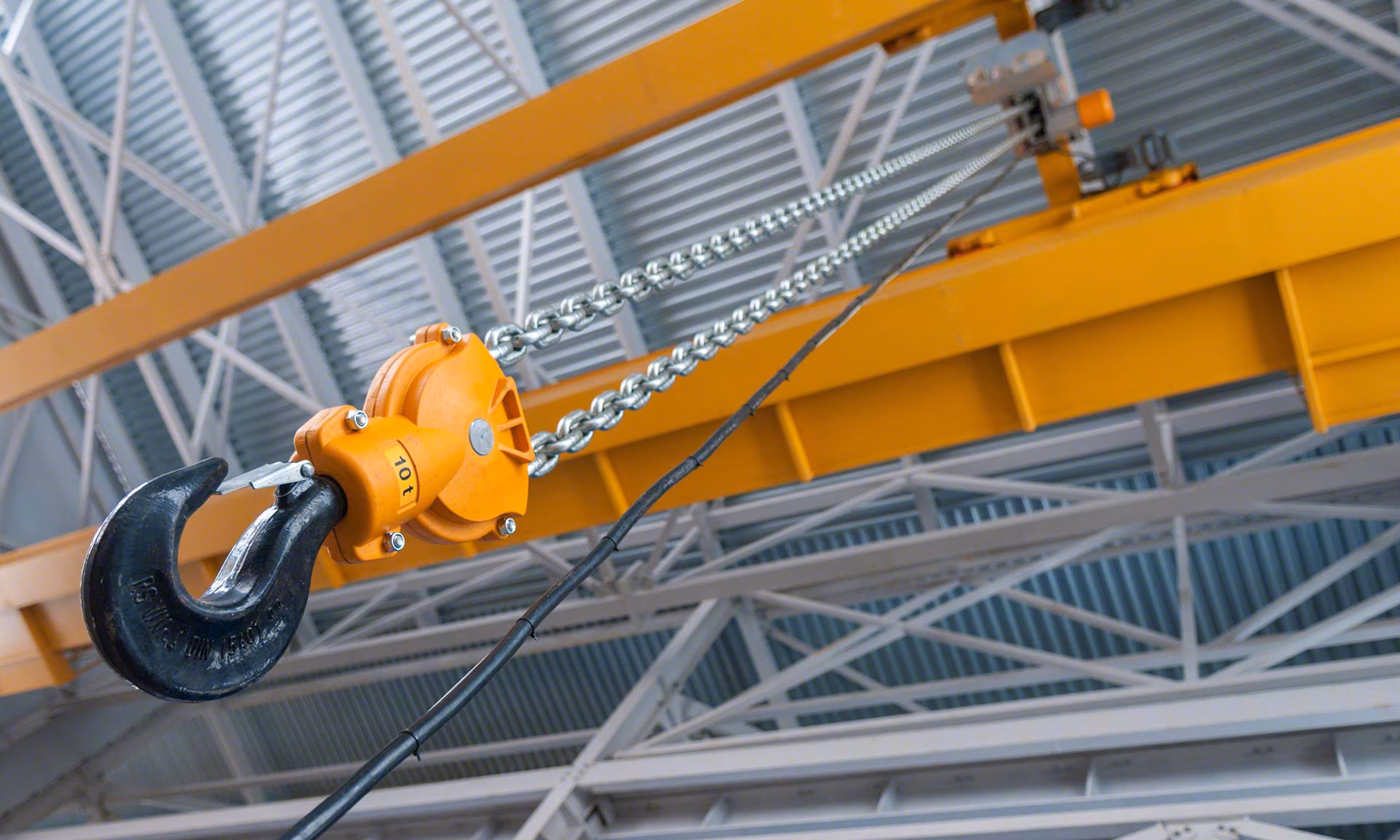 Polipasto de cadena sobre puente-grúa amarillo en nave industrial